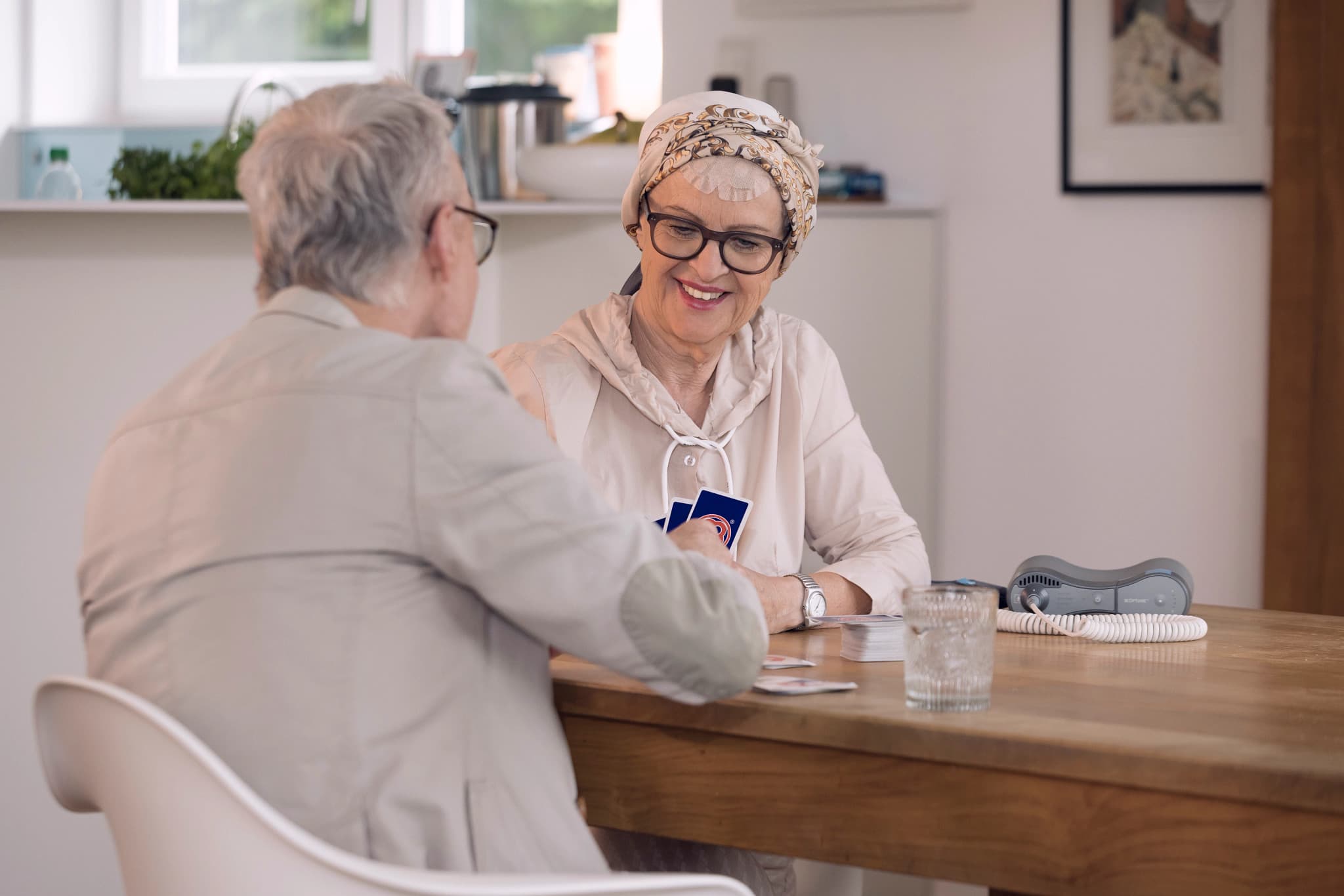 Smiling man wearing white shirt and wristwatch sitting outdoors with greenery background